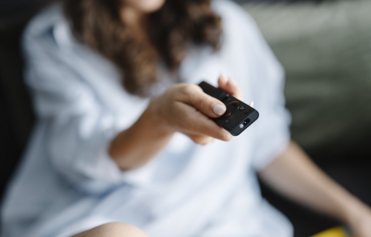 A person using a remote control while watching television